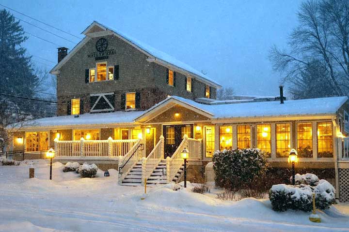 Outdoor patio seating surrounded by lush greenery at Water Wheel Tavern